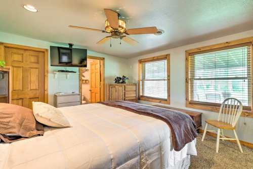 Cozy bedroom with a ceiling fan, large bed, wooden furniture, and windows letting in natural light.