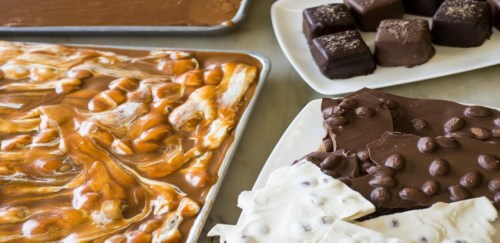 A variety of chocolates and confections, including caramel swirls, chocolate squares, and bark with coffee beans.