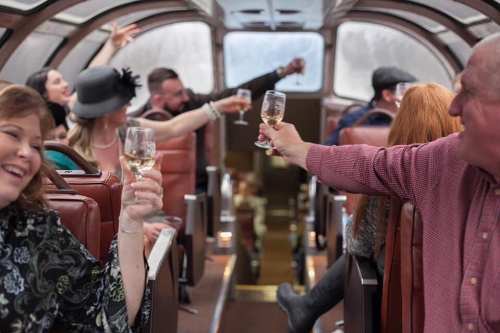 A group of people celebrating inside a train car, raising glasses and enjoying a festive atmosphere.