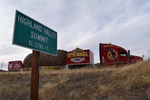 A green sign reads "Highland Valley Summit EL 3782 FT" next to a red truck with a large advertisement.