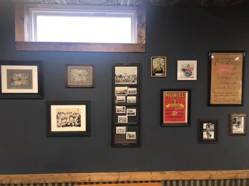 A wall display featuring various framed photos and a sign, showcasing historical images and memorabilia.