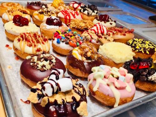 A colorful assortment of decorated donuts with various toppings on a tray.