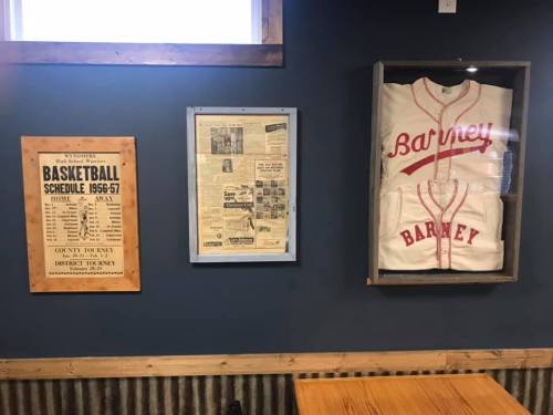 A wall display featuring a vintage basketball schedule, newspaper clippings, and a framed jersey labeled "Barney."