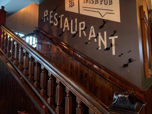 Staircase with wooden railing leading to a wall featuring the word "RESTAURANT" in bold letters, partially damaged.