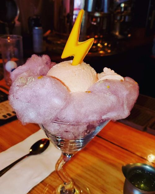 A dessert featuring a scoop of ice cream atop fluffy cotton candy, topped with a yellow lightning bolt decoration.