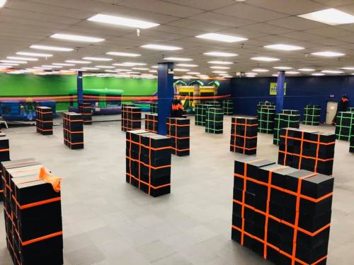 A spacious indoor area filled with black boxes outlined in orange, arranged in a grid pattern. Brightly lit with colorful walls.