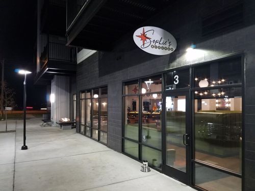 Exterior view of Sophie's restaurant at night, featuring large windows and a modern sign.