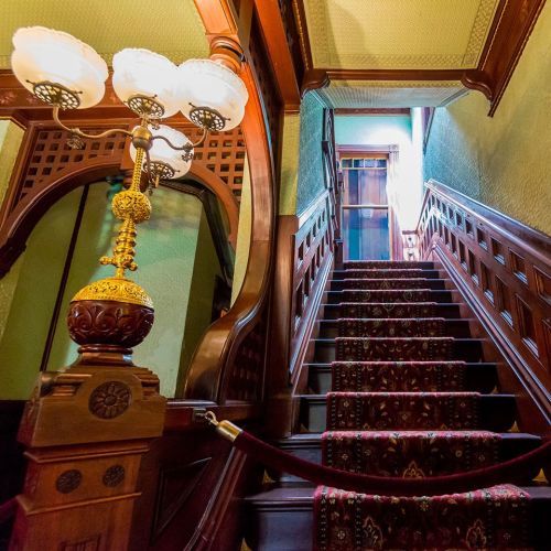 A beautifully crafted wooden staircase with ornate details, leading to a softly lit upper level.
