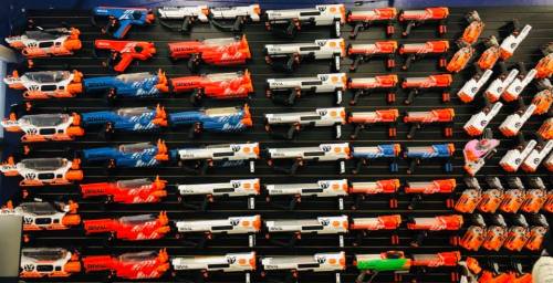 A display wall featuring various toy blasters in red, blue, and white, arranged in neat rows.