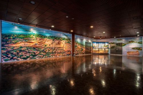 A spacious gallery featuring vibrant murals of a historical landscape and a display area with informational panels.