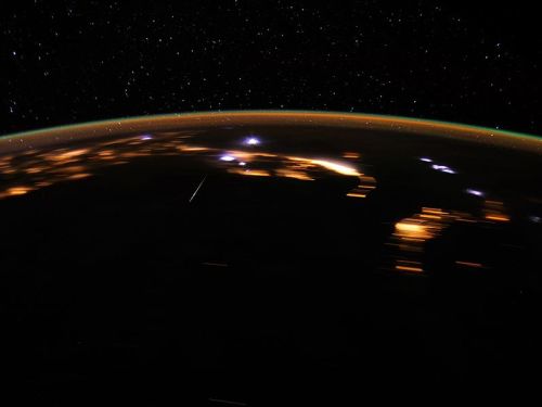A view of Earth from space, showcasing city lights and a starry sky above the planet's curved horizon.