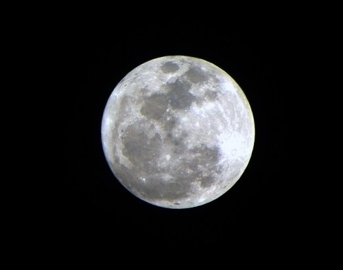 A close-up view of a full moon against a black sky, showcasing its craters and surface details.