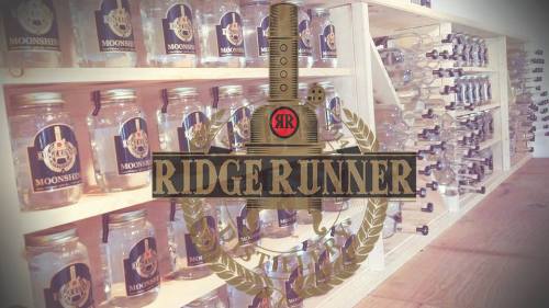 Display of jars labeled "Ridge Runner Moonshine" on shelves, with a logo featuring a sword and laurel wreath.