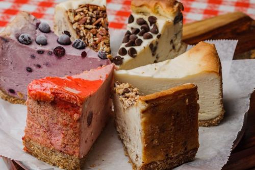 A variety of colorful cheesecake slices arranged on a plate, featuring flavors like berry, chocolate, and plain.