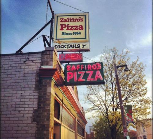 Sign for Zaffiro's Pizza, established in 1954, featuring "Open" and "Cocktails" in bright neon lights.