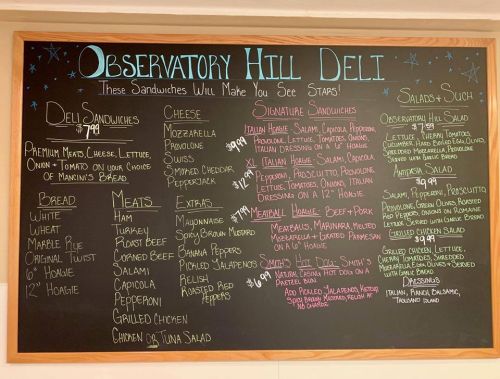 Chalkboard menu featuring deli sandwiches, salads, and extras with prices at Observatory Hill Deli.