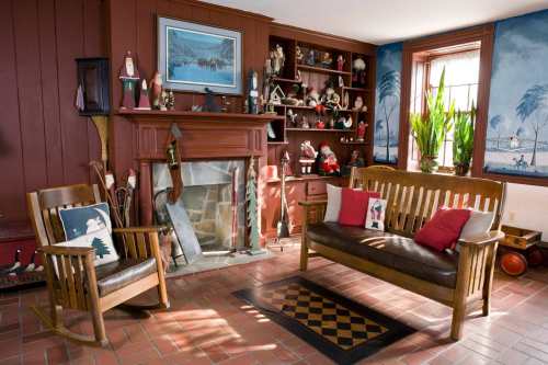 Cozy living room with a wooden sofa, rocking chair, fireplace, and shelves filled with decorative items and plants.