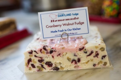 A block of cranberry walnut fudge with a sign reading "Homemade" on a marble countertop.