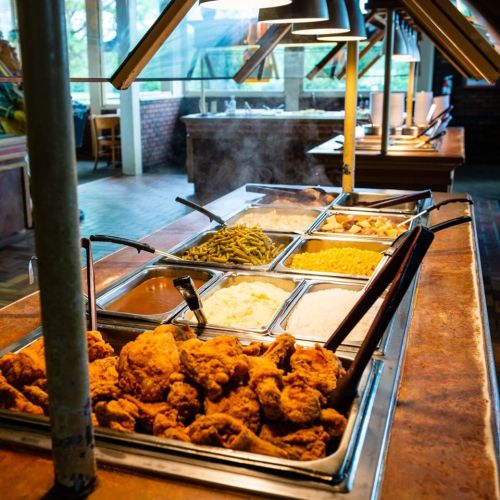 A buffet with various dishes, including fried chicken, green beans, mashed potatoes, and macaroni and cheese.