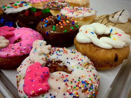 A variety of colorful donuts topped with sprinkles, frosting, and decorations on a tray.