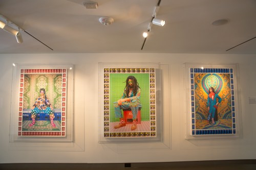 Three colorful framed artworks displayed on a gallery wall, featuring vibrant patterns and stylized figures.