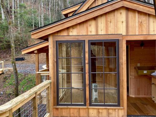 A wooden cabin with large windows, surrounded by trees, showcasing a cozy interior space.