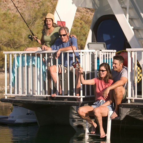 A group of four people fishing from a boat, enjoying a sunny day by the water.