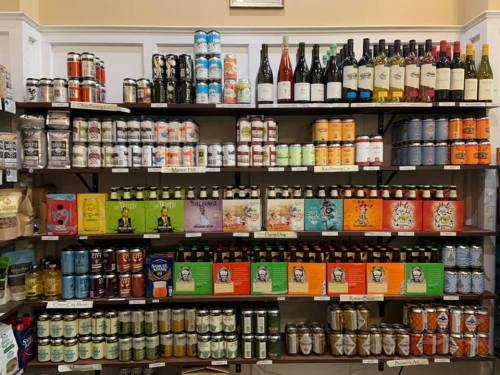 A colorful display of various canned goods, sauces, and wines arranged neatly on wooden shelves.