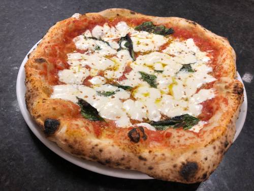 A freshly baked pizza with a golden crust, topped with mozzarella, basil, and a drizzle of olive oil.