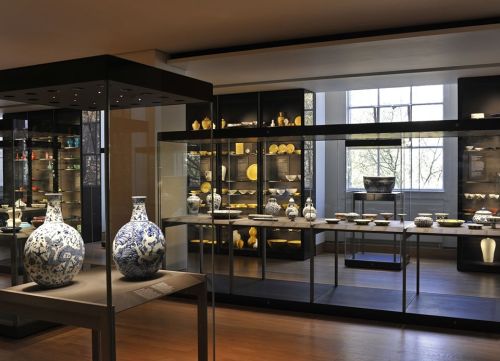 A museum display featuring various ceramic artifacts in glass cases, with blue and white vases prominently featured.