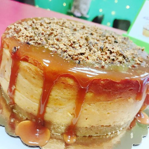 A delicious caramel cake topped with crushed nuts and a glossy caramel drizzle, sitting on a silver platter.