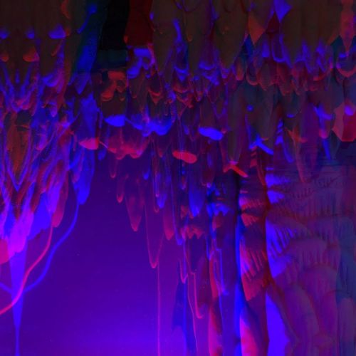 Abstract image featuring vibrant blue and purple shapes resembling dripping stalactites or fluid forms.