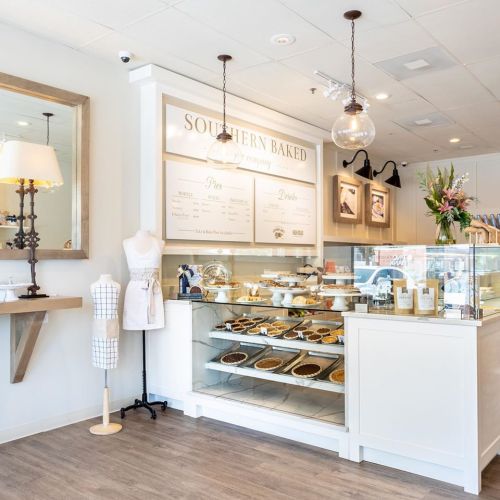 A bright bakery display showcasing various pies and desserts, with a stylish interior and decorative elements.