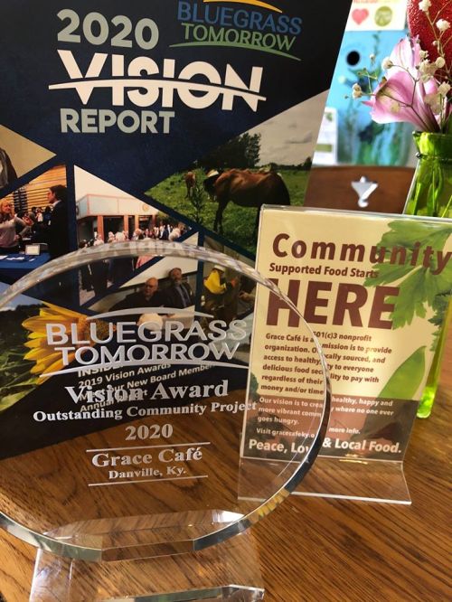 A glass award for the 2020 Bluegrass Tomorrow Wish Award, featuring details about Grace Café and community support initiatives.