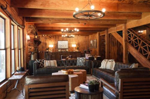 Cozy rustic living room with leather sofas, wooden beams, and warm lighting, featuring a stone fireplace and decorative accents.