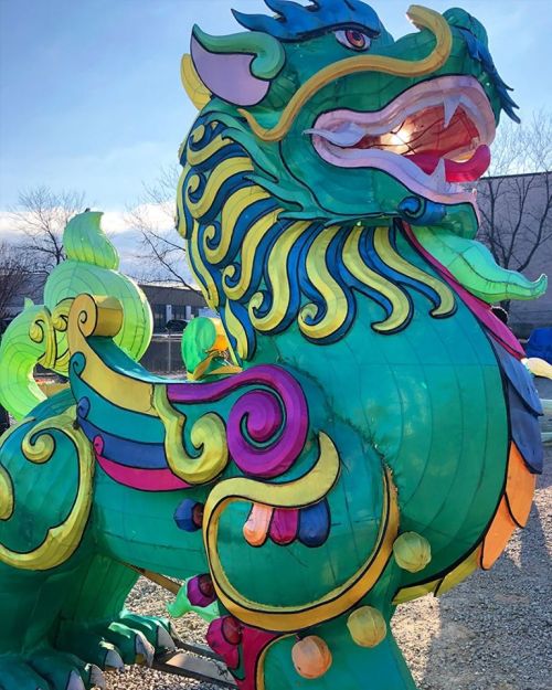 A colorful, large dragon lantern with intricate designs, set against a clear blue sky.