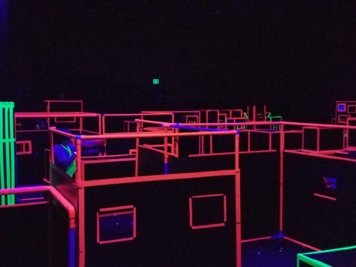 A dark room filled with neon-lit maze structures in pink and green, creating a vibrant, playful atmosphere.