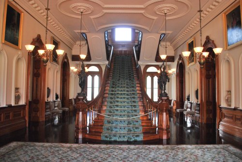 Grand entrance hall featuring a staircase, ornate ceiling, wooden accents, and elegant lighting fixtures.