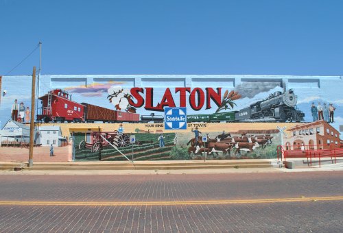 Colorful mural in Slaton, Texas, depicting trains, agriculture, and local history against a bright blue sky.