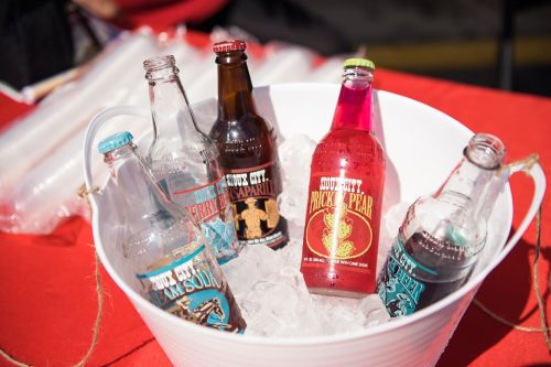 A bucket filled with ice containing various colorful soda bottles.