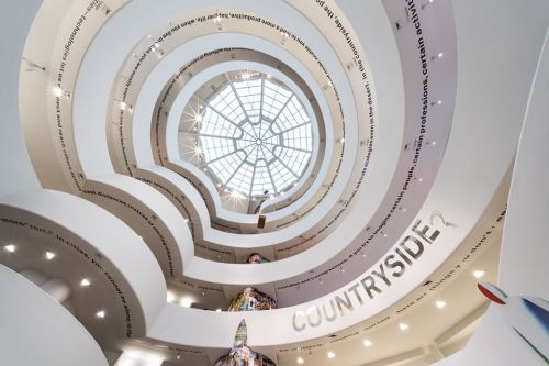 A spiral staircase with a glass dome ceiling, featuring the word "COUNTRYSIDE" and illuminated by bright lights.