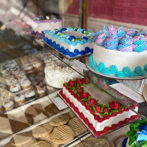 A display of colorful cakes and pastries, featuring decorated frosting and various designs in a bakery setting.