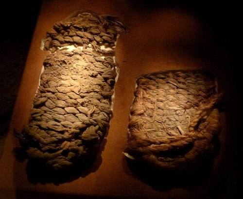 Two ancient mummies displayed under soft lighting, showcasing their intricate wrappings and textures.