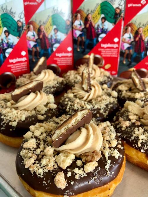 Delicious donuts topped with chocolate, cream, and cookie crumbles, with Girl Scout cookie boxes in the background.
