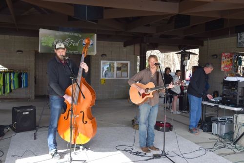 Two musicians perform on stage; one plays a double bass while the other sings and plays guitar.