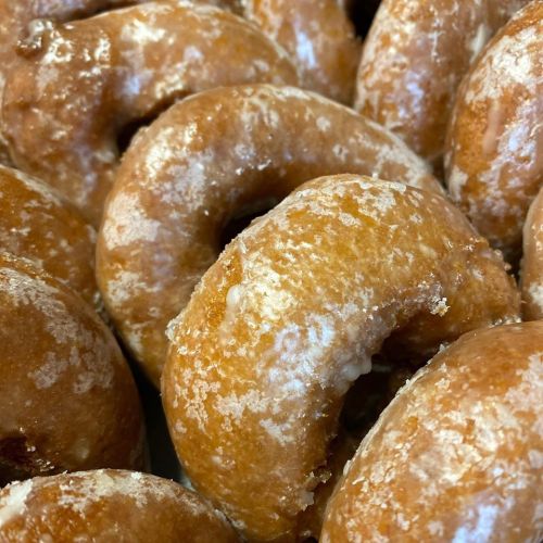 A close-up of freshly glazed donuts, showcasing their golden-brown color and sugary coating.