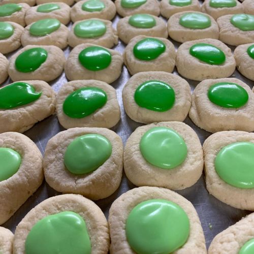 A tray of cookies with a light-colored base and bright green frosting in the center.