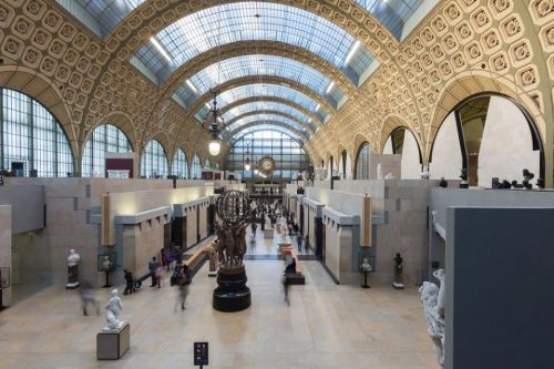 Interior of the Musée d'Orsay, featuring high ceilings, sculptures, and visitors exploring the art-filled space.