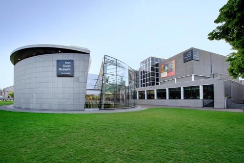 Exterior view of the Van Gogh Museum in Amsterdam, featuring modern architecture and green lawn.