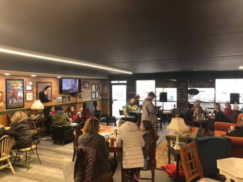 A cozy café scene with people chatting, sitting at tables, and enjoying drinks in a warm, inviting atmosphere.